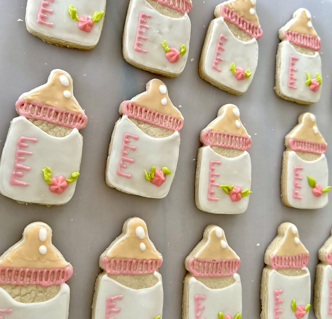 Baby bottle cookies with pink accents and floral details